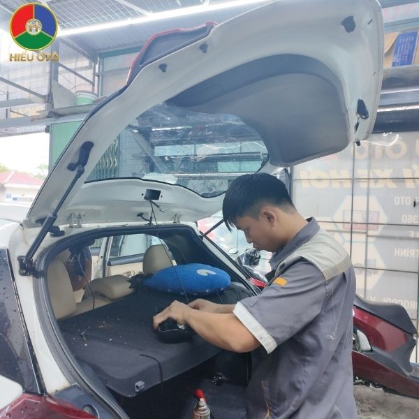 Kỹ thuật viên đang thi công đi dây ngầm an toàn cho camera sau tại khu vực cốp xe.