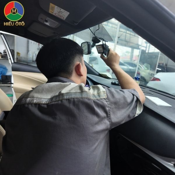 Kỹ thuật viên đang căn chỉnh và dán cố định camera trước 70mai A800SE lên kính lái ô tô.